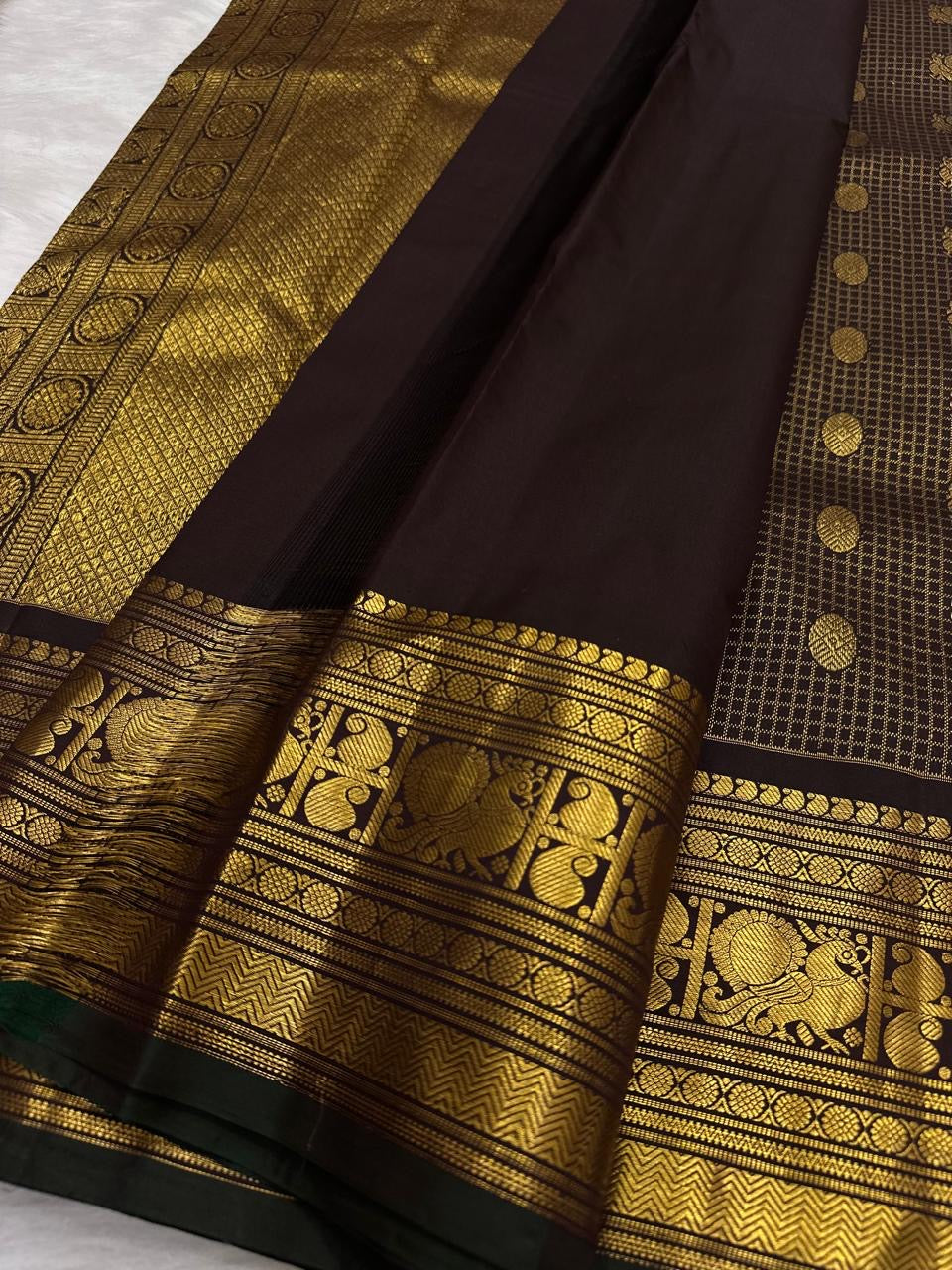 Ornate self-colour border of deep brown lightweight Kanjivaram saree with Mayil peacock elephant and geometric antique gold zari