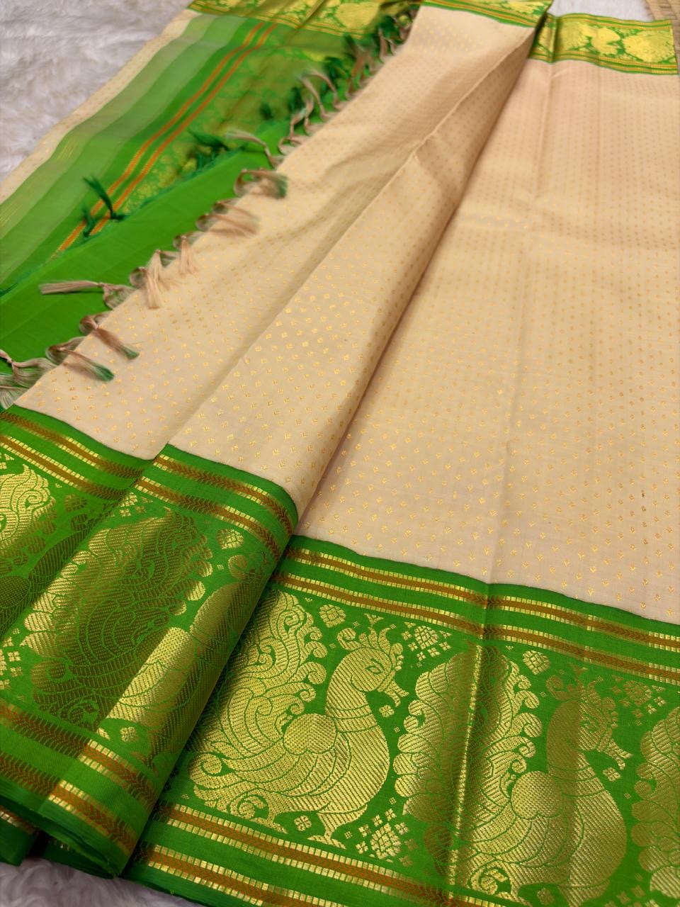 Emerald green Korvai border detail with antique-gold zari peacock motifs on soft ivory Kanjipuram saree