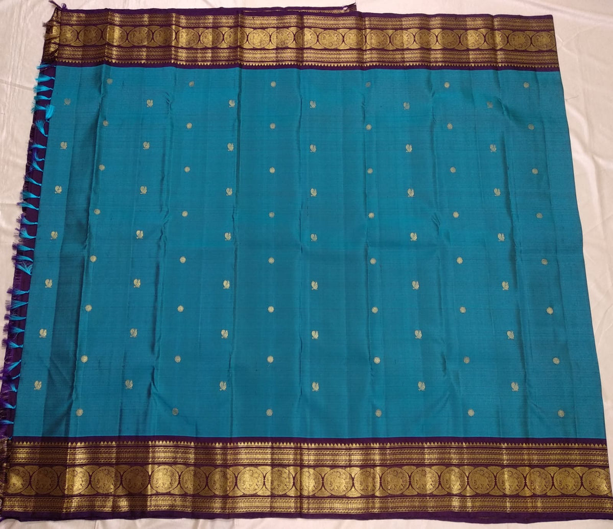 Close view of handwoven gold zari buttas on Turquoise Blue Korvai saree