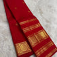Handwoven kumkum red Kanchipattu saree with Rettapet zari border, full drape view.