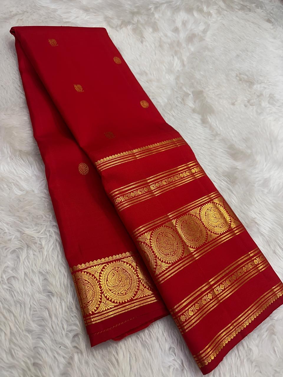 Handwoven kumkum red Kanchipattu saree with Rettapet zari border, full drape view.