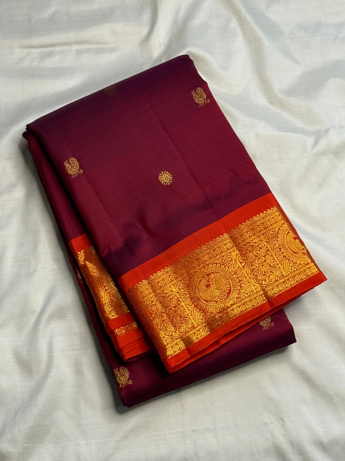 Alternating gold-zari buttas across garnet-maroon silk.