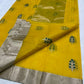 Yellow saree with green leaf patterns and silver border on a white background