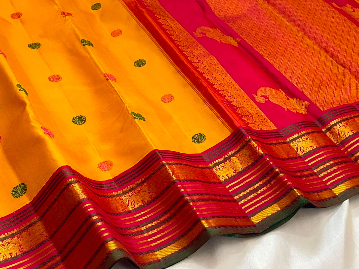 Handwoven golden turmeric Kanchipuram saree with raspberry pink zari border.