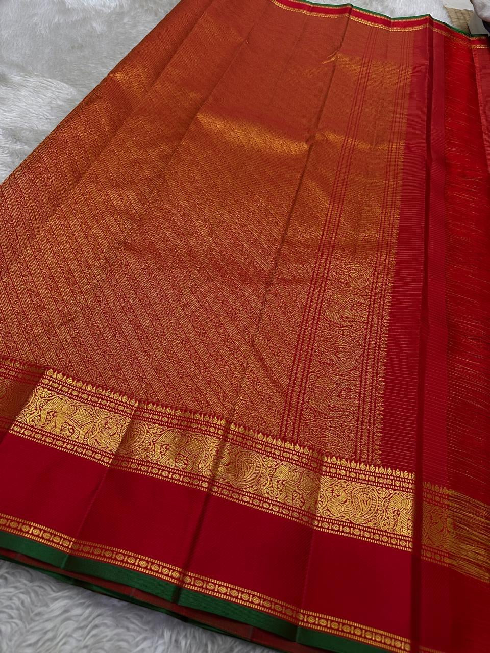 Small gold zari buttas across glowing Sindoor red Kanjipuram silk with delicate lattice weave
