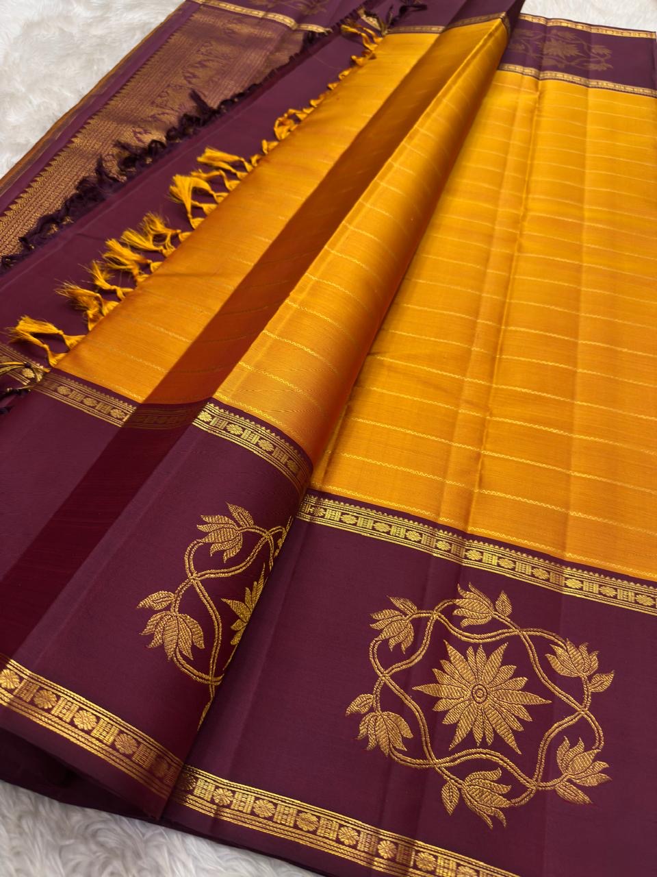 Handwoven turmeric gold Kanchipuram silk rettapet saree with Vadamalli plum border.