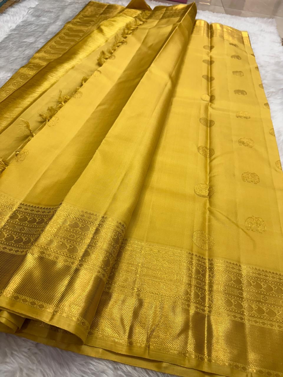 Full view of Manjal yellow handwoven Kanchipuram silk with Kamalam buttas and detailed zari border.