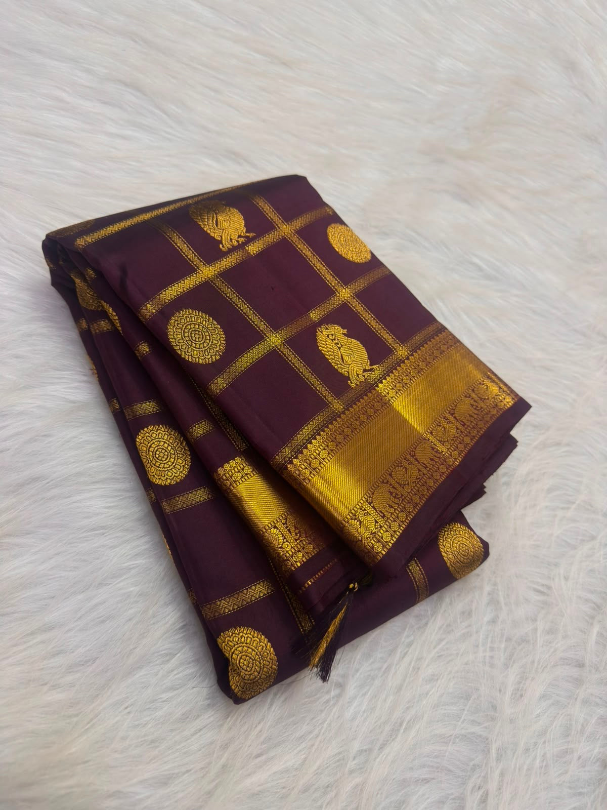 Handwoven Zari Kattam saree in deep aubergine with Mayil Chakram motifs, folded view