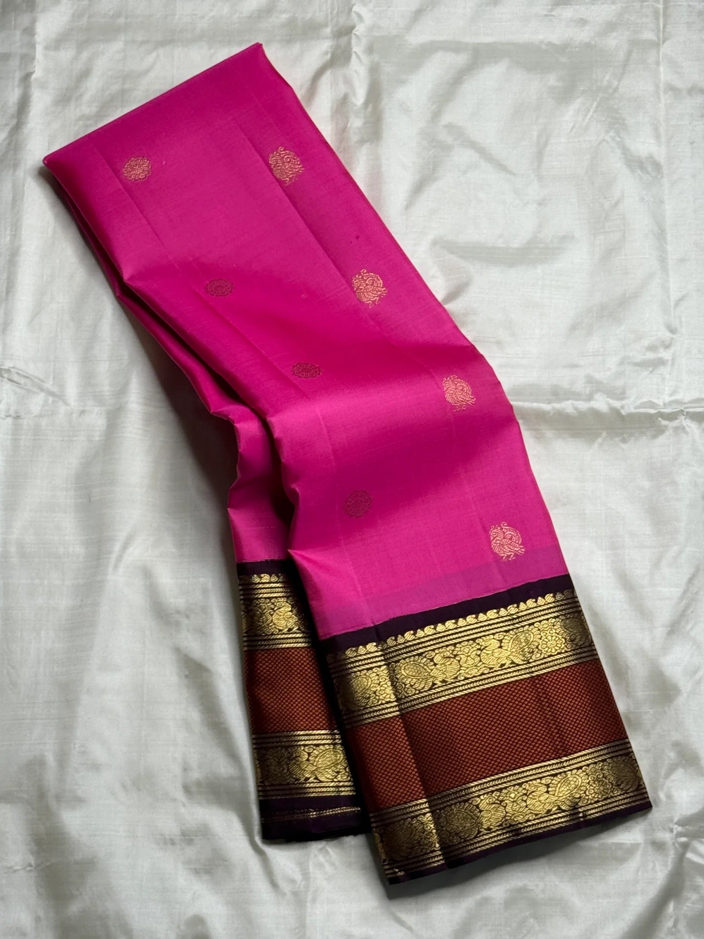 Bright pink Kanjivaram silk saree with traditional gold zari peacock motifs and heritage brown korvai border