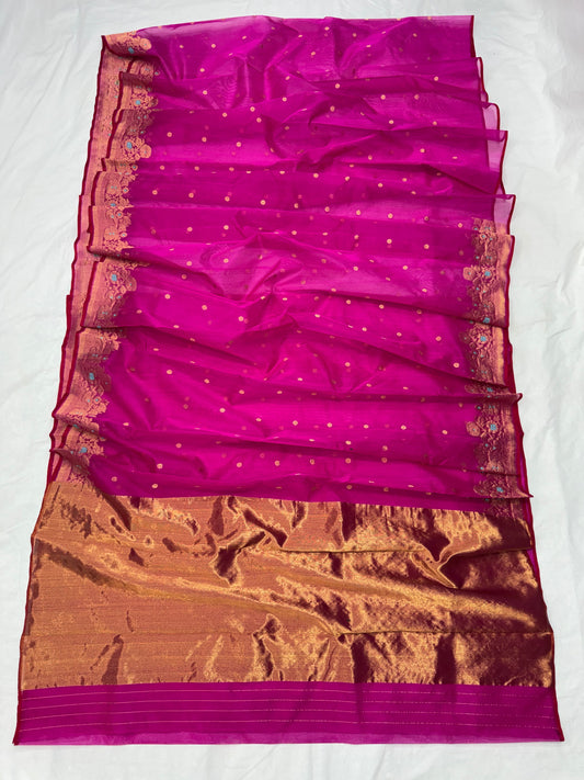 Purplish pink Katan silk Chanderi saree laid open showing small gold-toned buttas and broad antique-gold floral border with turquoise accents