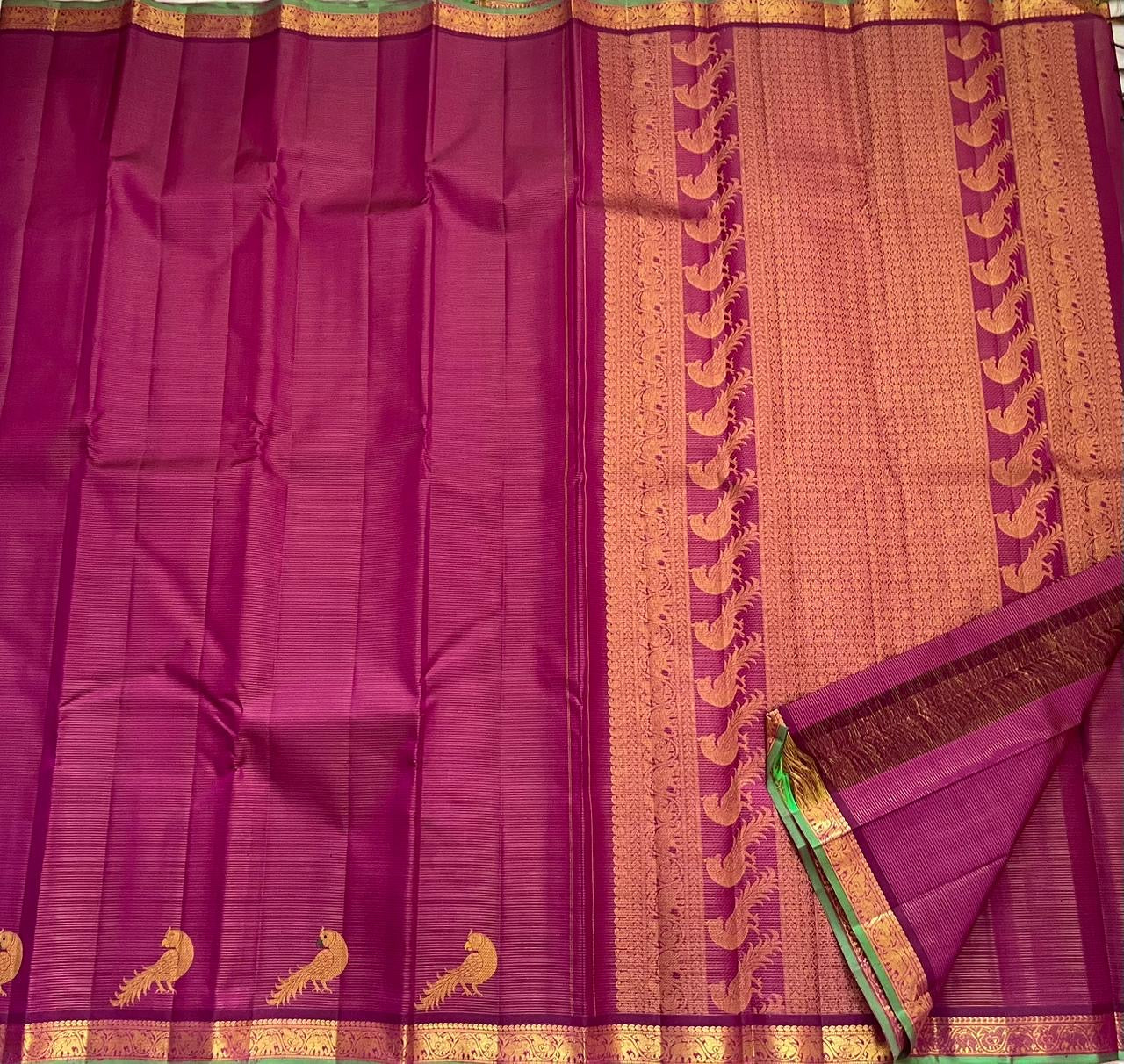 Folded hot pink Kanjipuram pure silk saree showing Vairaoosi zari shimmer body and green contrast border