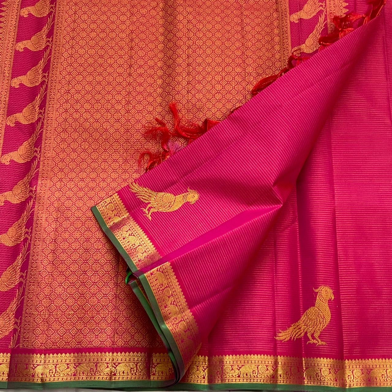 Ornate parrot Kili Butta gold zari pallu of hot pink Kanchipuram saree on green ground