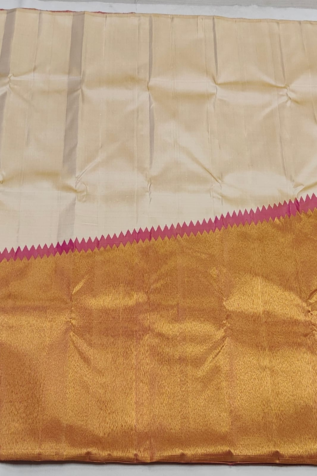 Close view of pink temple border on cream Kanchipuram silk saree with antique gold zari