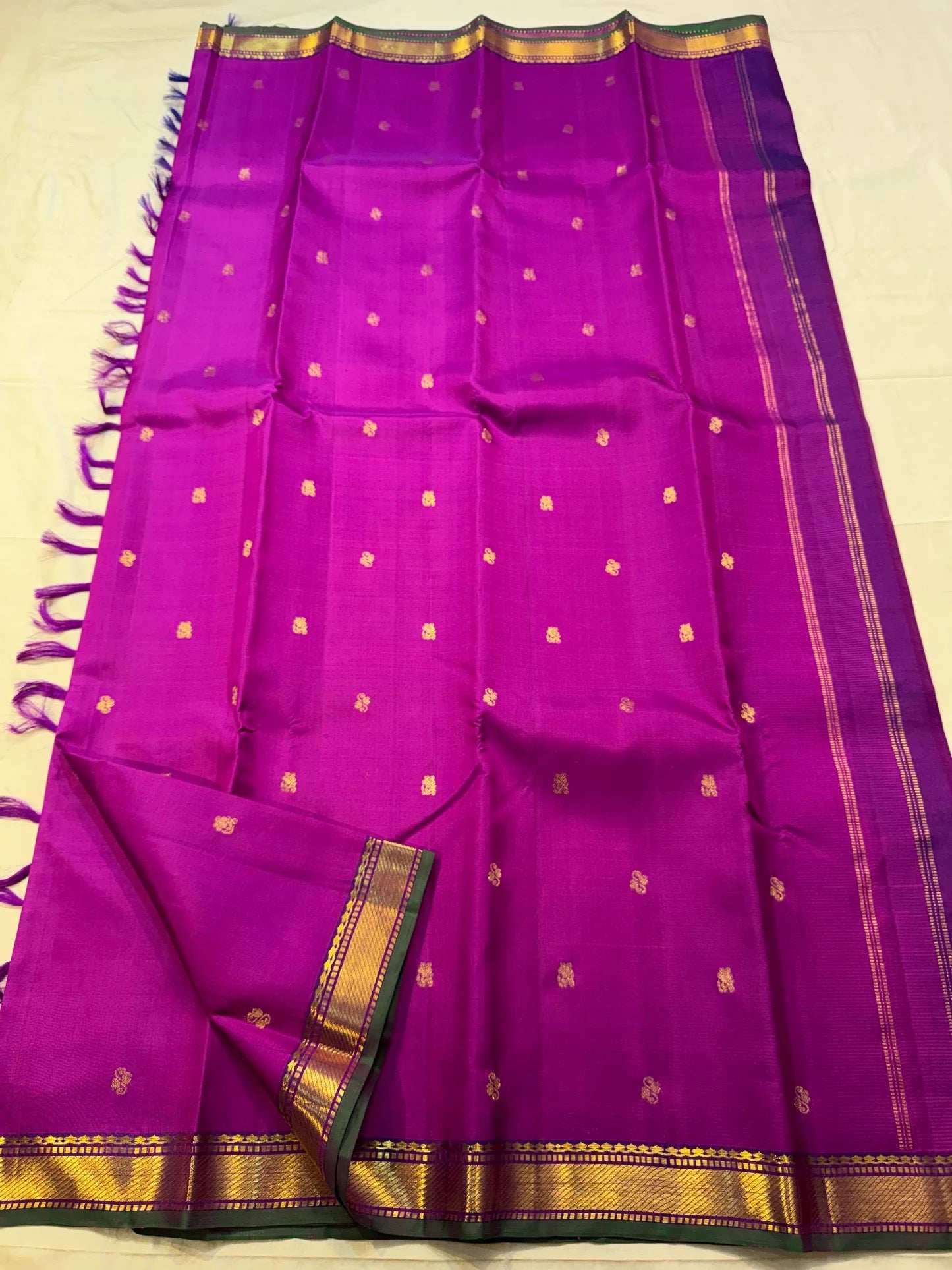 Pure Kancheepuram silk saree featuring delicate floral buttas, traditional zari border, and elegant seer pallu