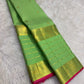 Close view of antique-gold traditional zari motifs woven on fresh green Kanjivaram silk.