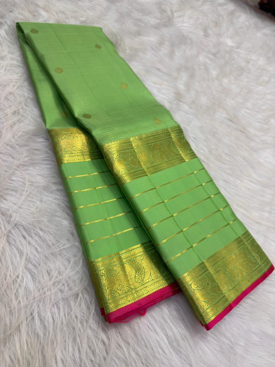 Close view of antique-gold traditional zari motifs woven on fresh green Kanjivaram silk.