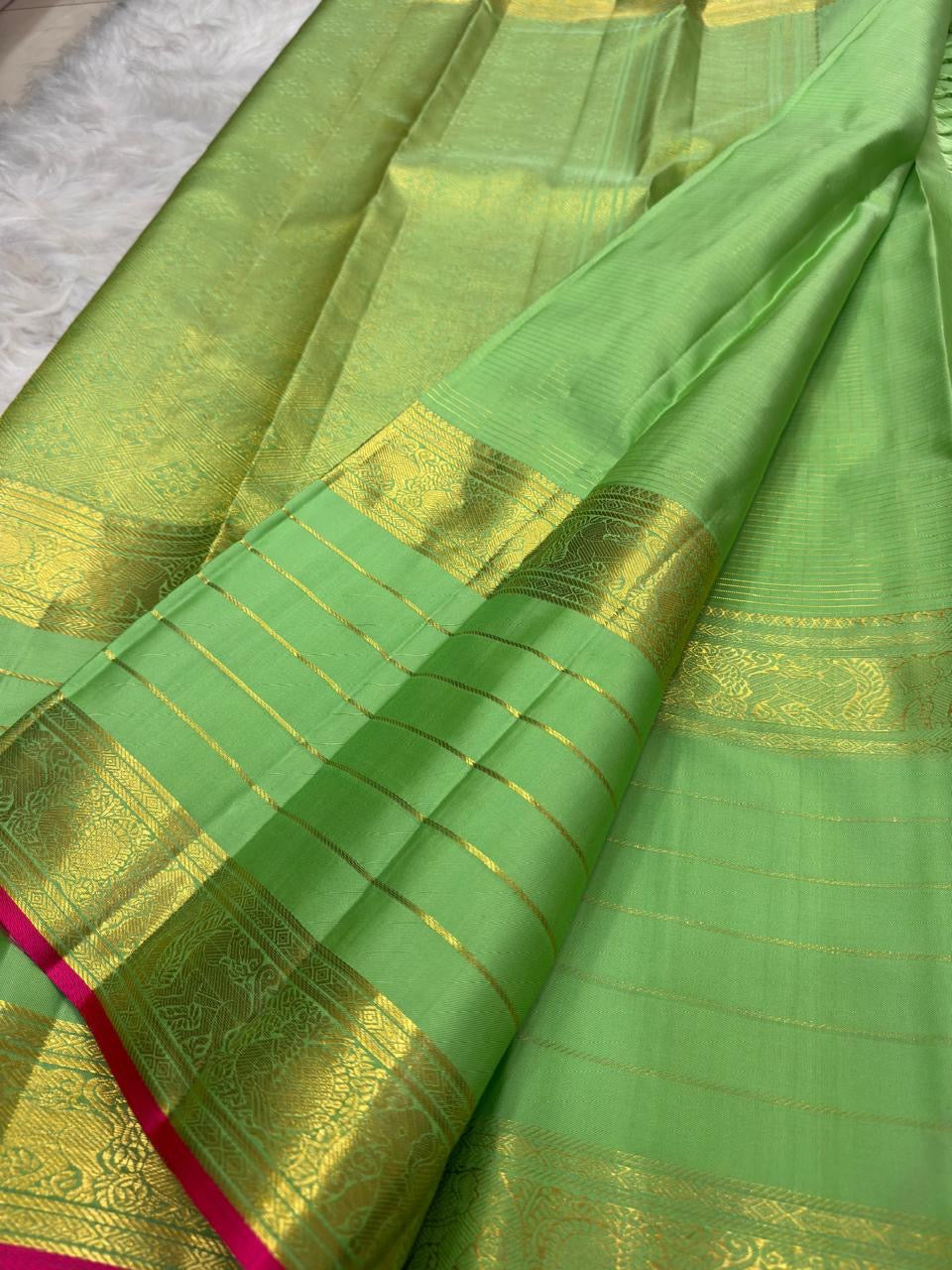 Leaf green Kanchipuram silk saree with spaced antique-gold zari buttas.