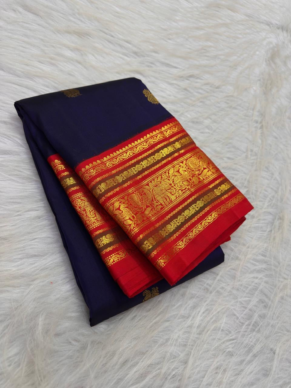 Deep navy Kanchipuram silk saree with spaced gold zari motifs and layered red Varisaipet border.