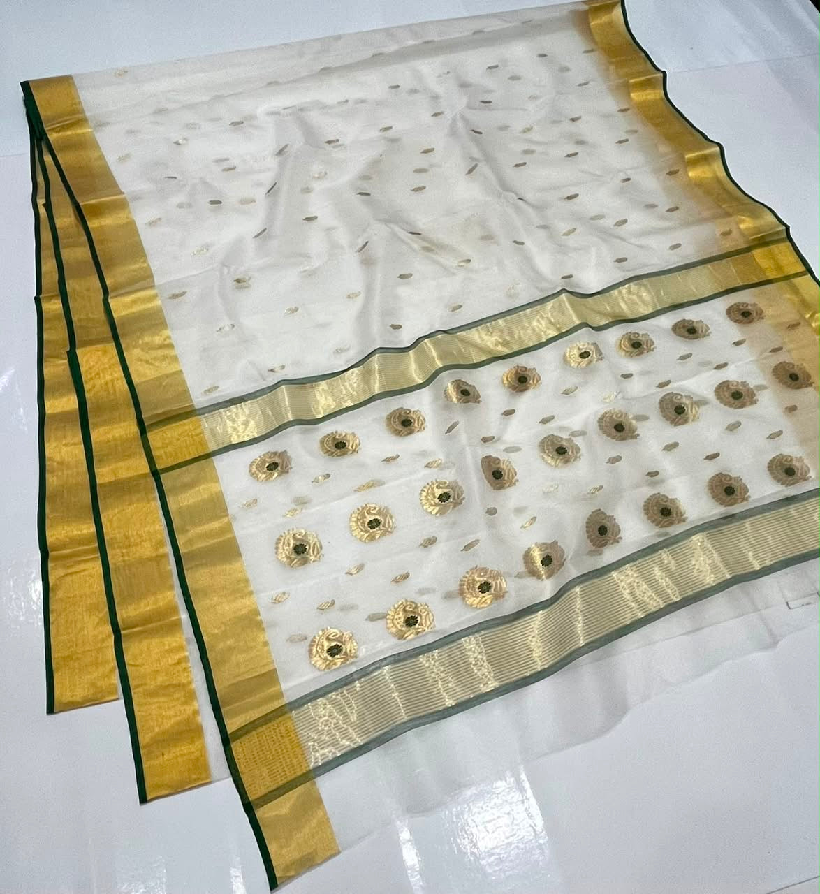 Ivory handloom Chanderi saree showing gold woven motifs, Emerald Green edged gold border and decorative pallu.