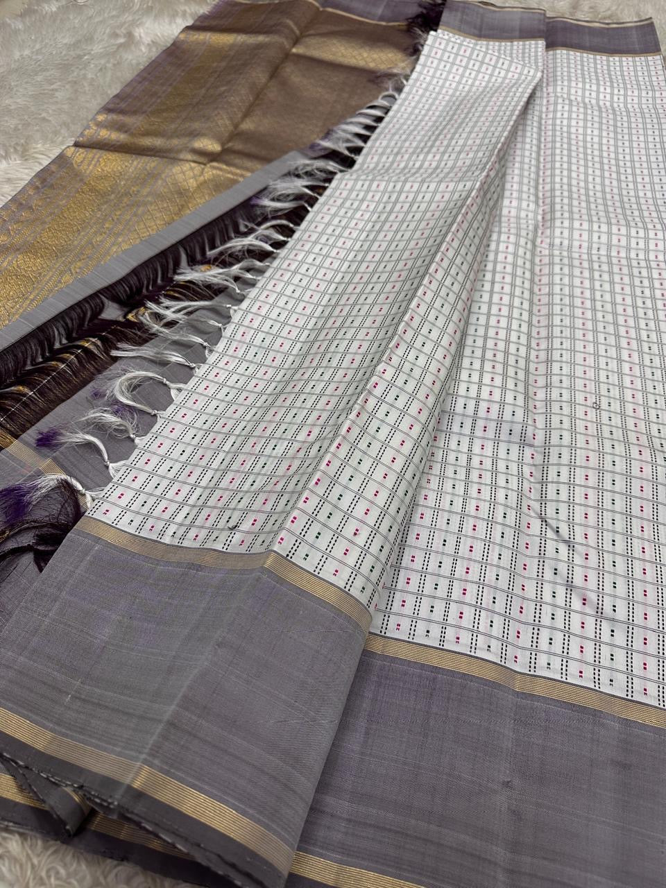 Full drape of pure Kanchipuram silk saree displaying ivory grid-patterned body with multicolour dotted detailing and soft grey border with gold zari accents.