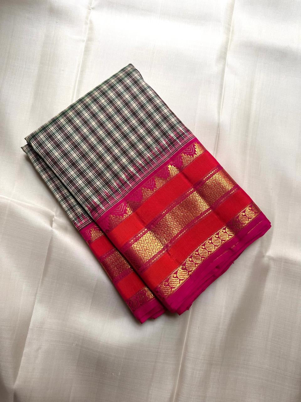 Transition from the ivory checked body into the raspberry-red gold zari border.