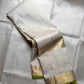 Soft ivory Kanchipuram silk saree with zari kattam grid, small antique gold buttas, and wide gold zari border with lime green selvedge