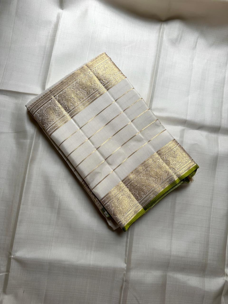 Ivory Kanchipuram silk saree folded to show gold zari border detailing and fine horizontal zari lines on the body