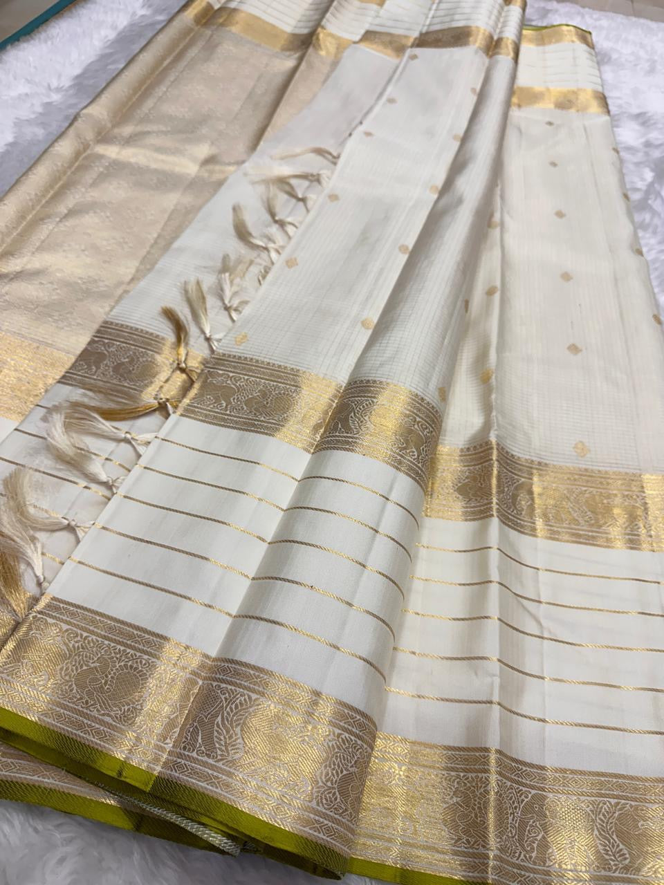 Ivory Kanchipuram silk saree draped to reveal zari kattam checks, antique gold buttas, broad zari border, and tasselled pallu