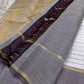 An ivory Kanchipuram silk saree featuring a fine grid pattern with subtle multicolour dotted accents, complemented by a soft grey border and gold zari detailing. The contrast pallu adds depth while maintaining visual balance.