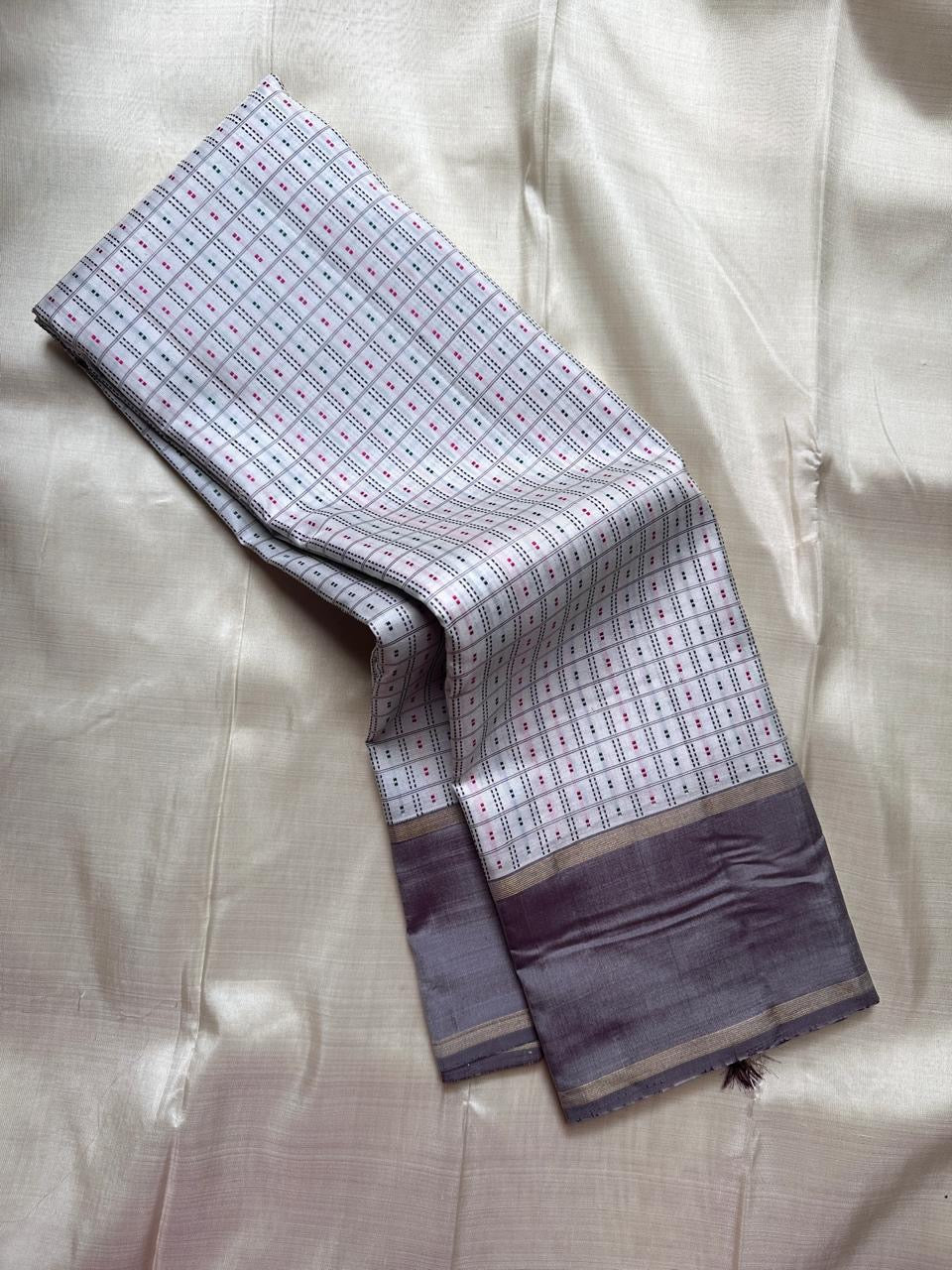 Close view of pure Kanchipuram silk saree showing soft grey silk border with classic gold zari stripes and a richly woven pallu in antique gold zari.