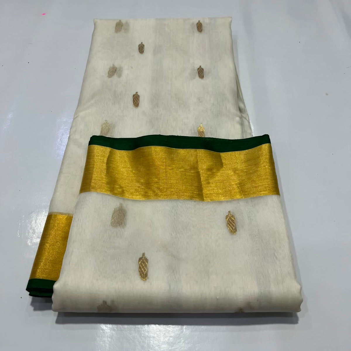 Ivory Katan Silk Chanderi saree showing the gold-tone border finished with a slender Deep Emerald Green edge.