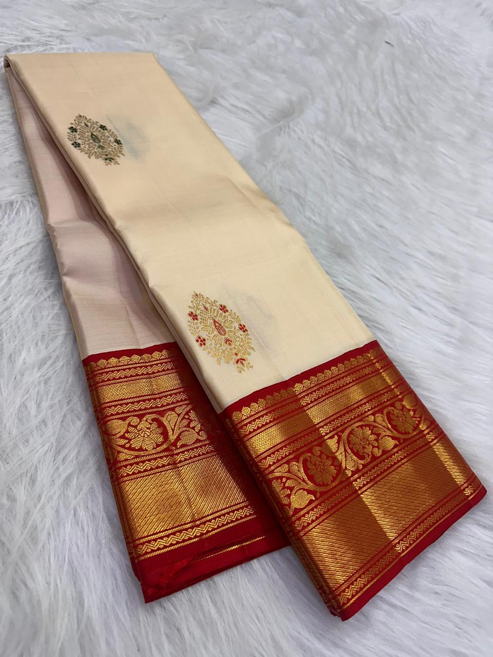 Handwoven ivory Korvai Kanchipuram silk saree with classic red and gold contrast framing.