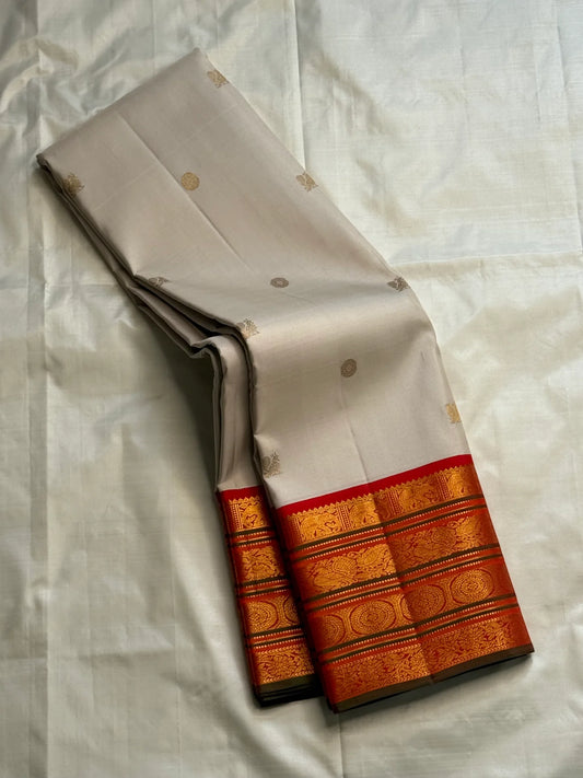Ivory Pure Kanchipuram Silk Saree drape showing scattered gold buttas and zari border with red edge