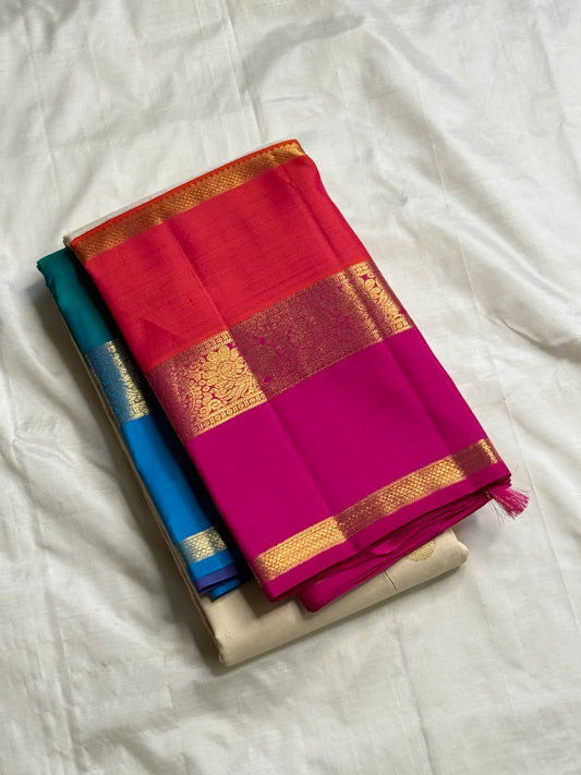 Folded ivory Kanchipuram silk saree with zari woven buttas and hot pink border over teal-blue layer.