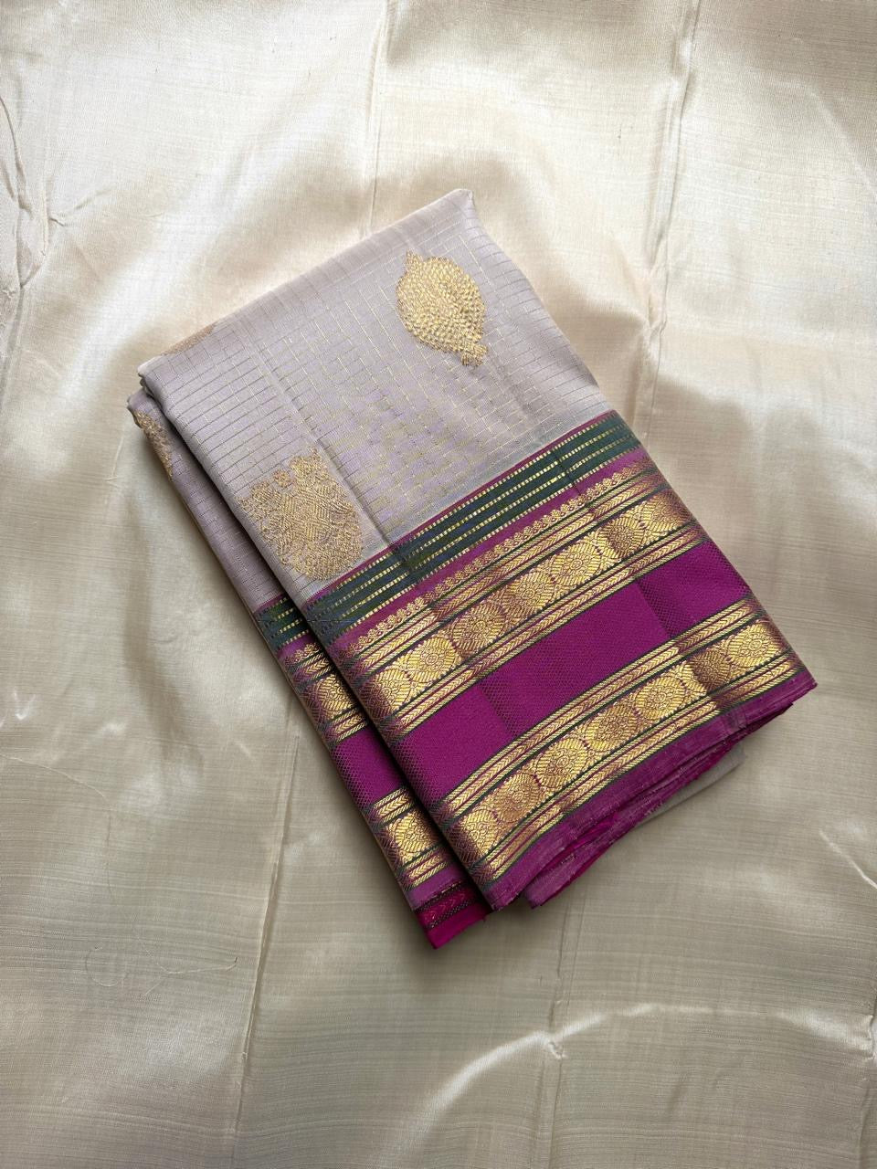 Folded pearl silver pure Kanchipuram silk saree with gold paisley buttas and magenta zari woven border