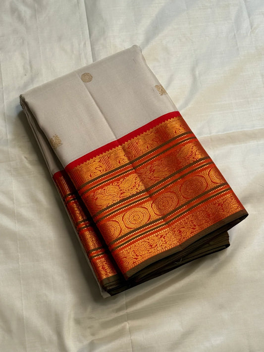 Folded ivory Pure Kanchipuram Silk Saree with small gold buttas and zari border with red edge