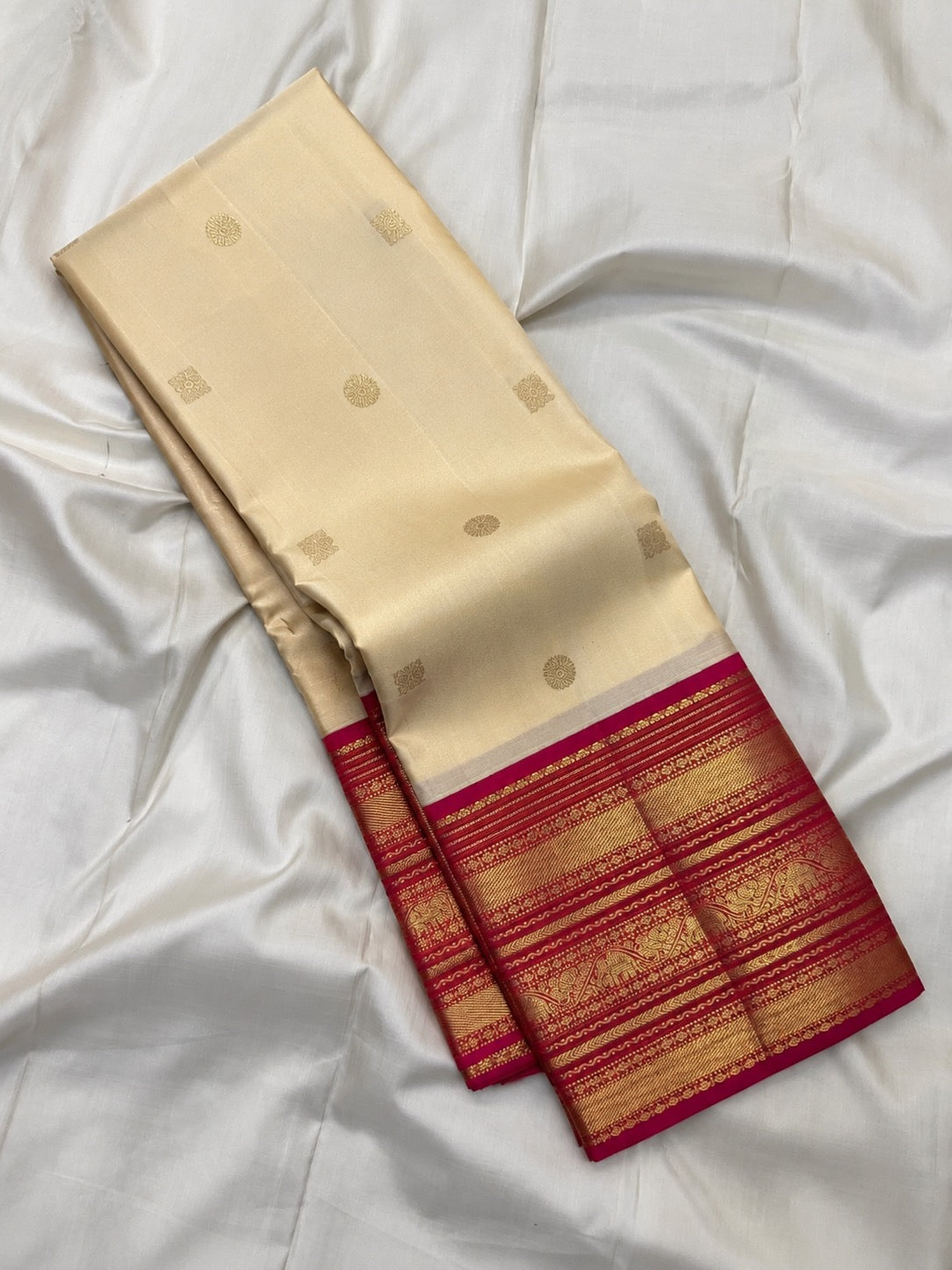 Close view of petite gold zari buttas on warm buttercream ivory Kanchipuram silk
