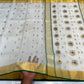 Folded Ivory Katan Silk Chanderi saree with small gold motifs, broad gold border and Deep Emerald Green edging.