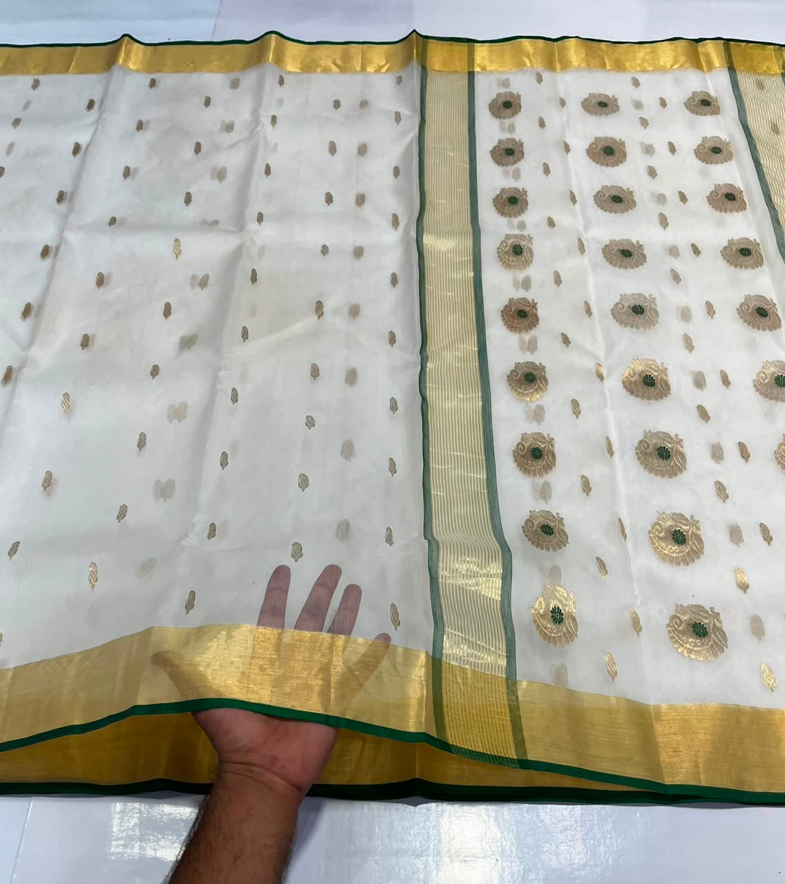 Folded Ivory Katan Silk Chanderi saree with small gold motifs, broad gold border and Deep Emerald Green edging.