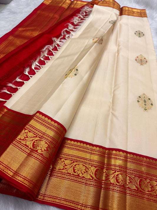 Ivory pure silk body showing spaced floral zari buttas and subtle green Meenakari accents.