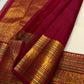 Handwoven ivory Kanchipuram body with small gold-zari buttas above a broad Arakku-red ornamental border.