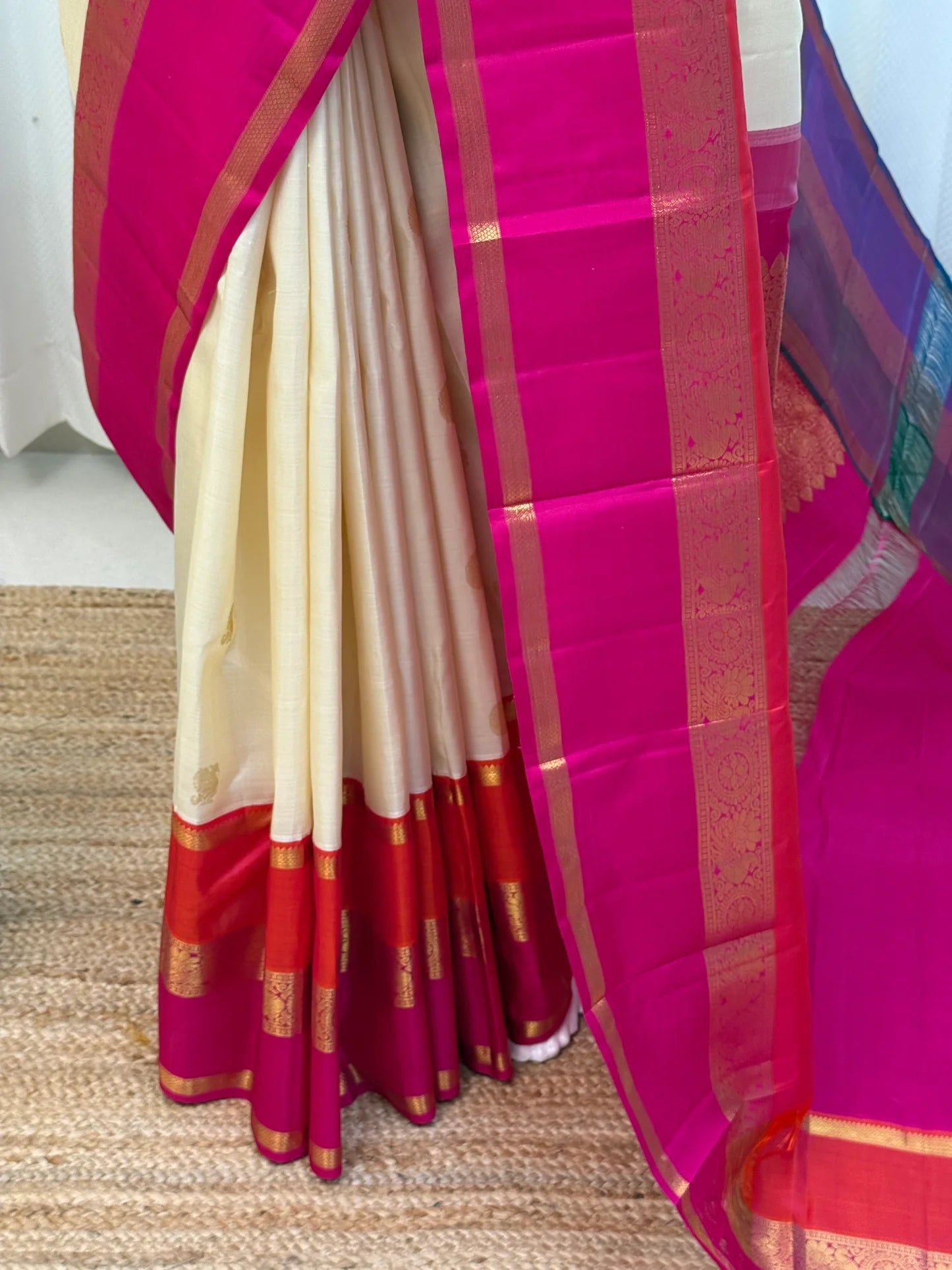 Mannequin drape of ivory Kanchipuram silk saree with hot pink zari woven border and teal-blue pallu band.