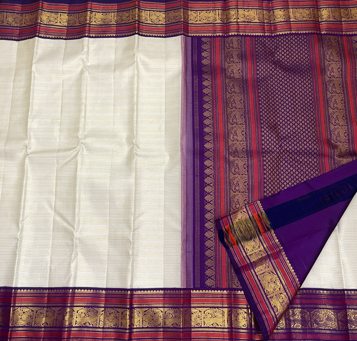 Warm Ivory Handwoven Pure Silk Kanchipuram Saree with Purple Border and Veldhari Detail, folded saree presentation