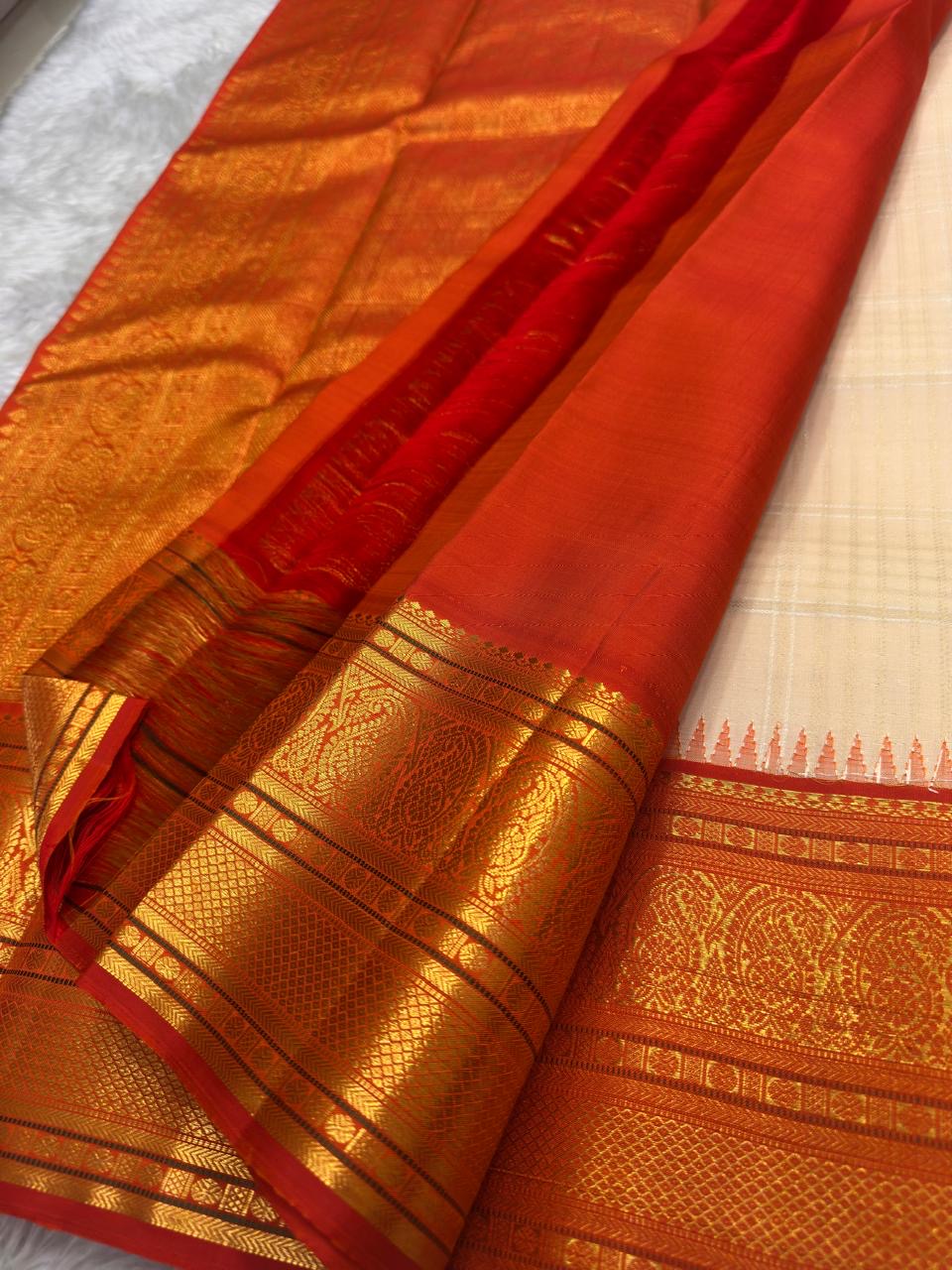 Elaborate Paisley motif pallu in dense gold on deep red Korvai ground of ivory Kancheepuram