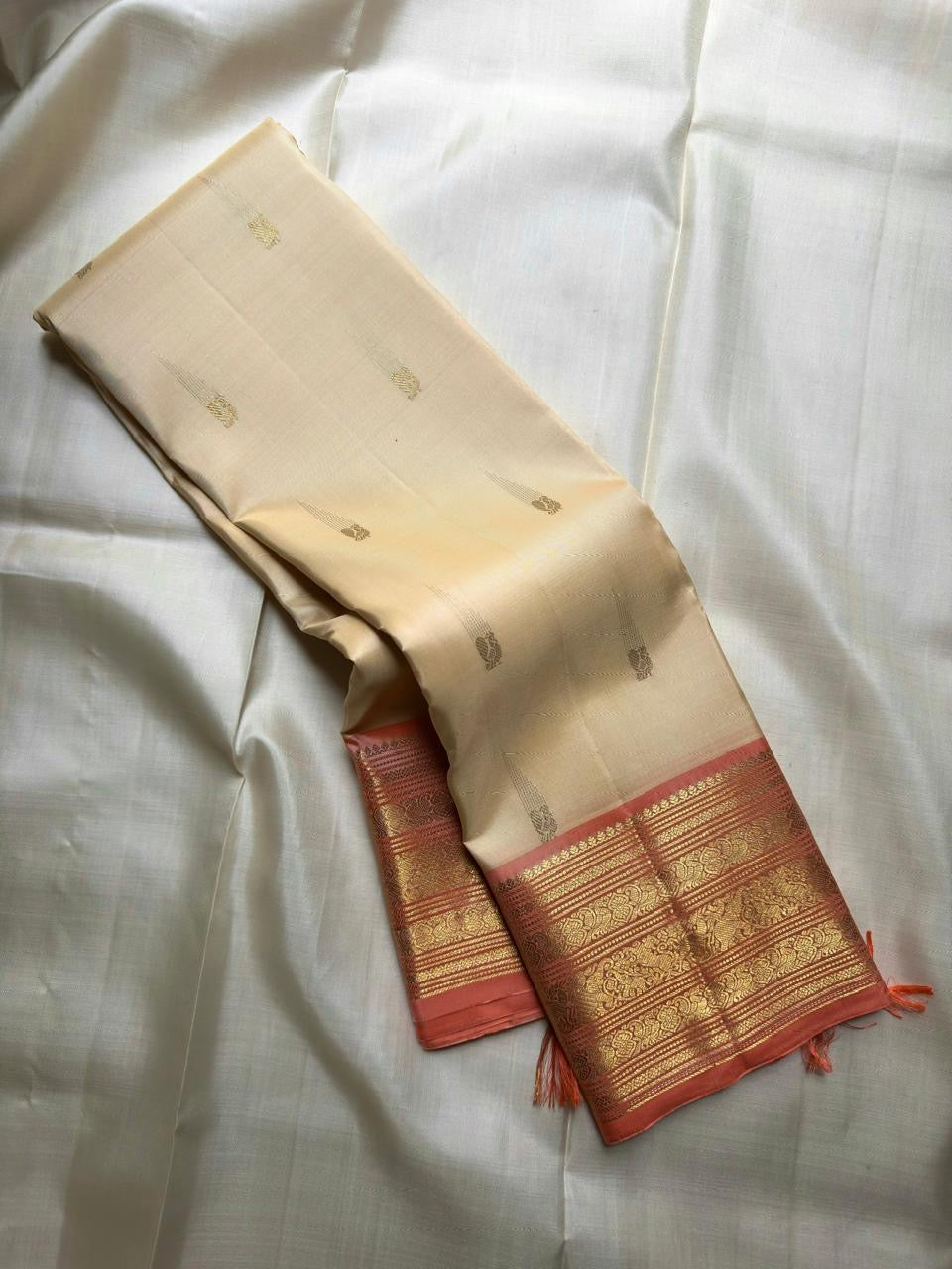 Close border detail showing traditional floral gold-zari ornament across soft Lotus Pink silk.