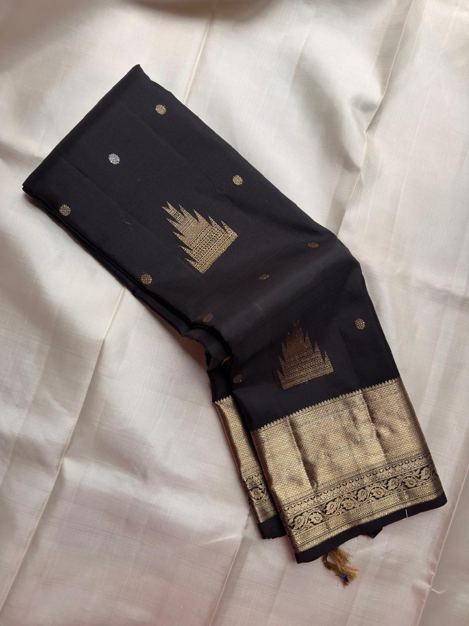 Jet Black pure silk Kanjivaram Butta saree with traditional Thazhampoo Reku zari motifs.
