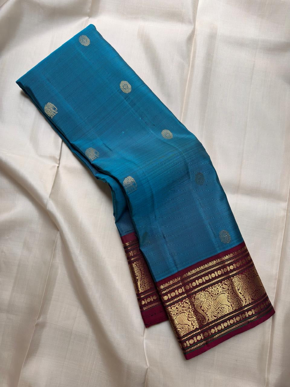 Kadal Neelam teal-blue Pure Silk Kanchipuram Butta saree with traditional gold buttas and Arakku border.