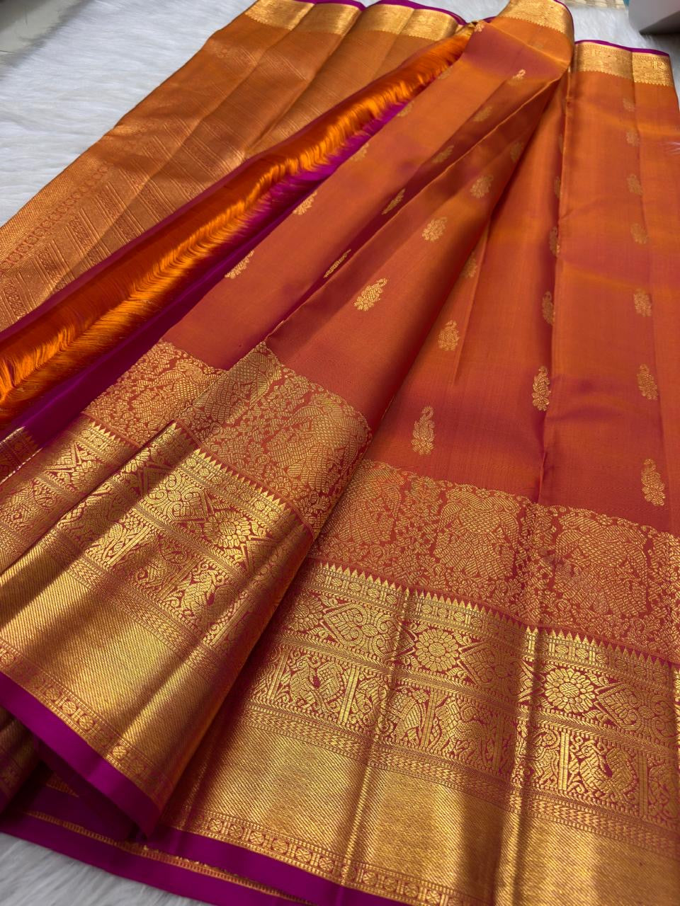 Coral-toned Kanakambaram Kanjeevaram silk with petite zari buttas and traditional Chakram border work