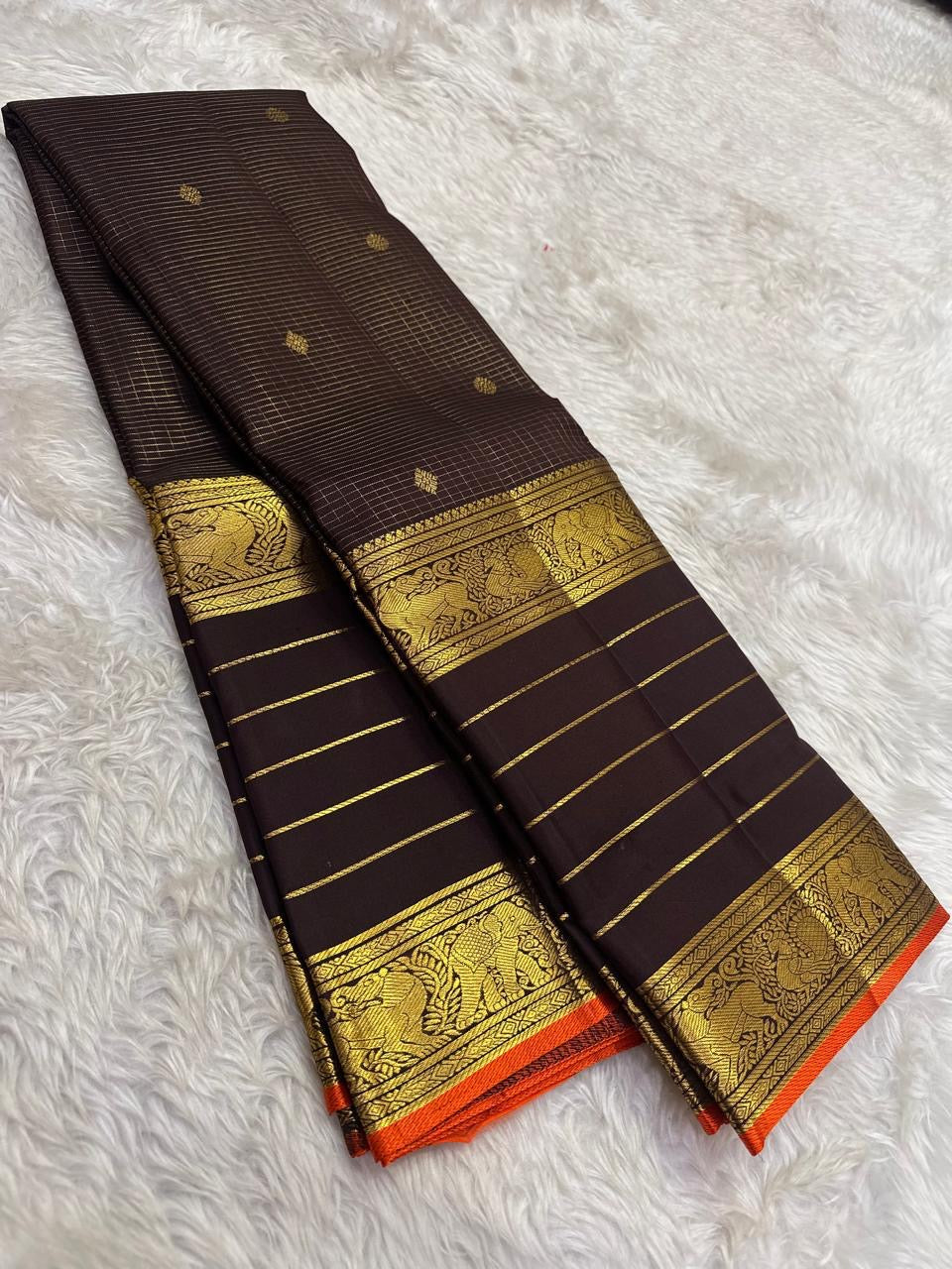 Close view of antique-gold traditional zari motifs woven on deep brown Kanjivaram silk.