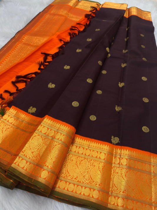 Kanchana Brown pure silk Kanchi Pattu Butta saree with vivid orange and gold zari peacock border.